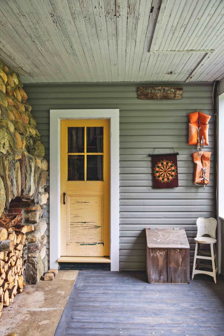 the entryway is flanked, in very maine fashion, by stacked logs and hanging lif 15