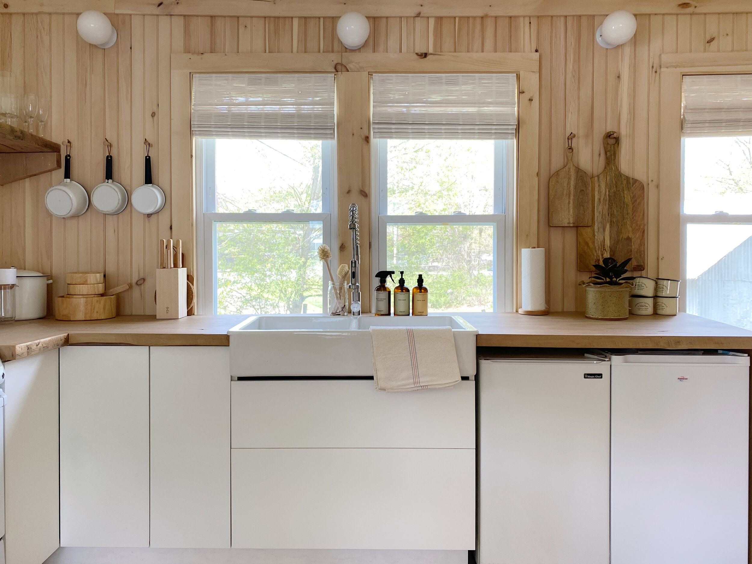 the kitchen is designed with plain white lower cabinets, reclaimed wood counter 17