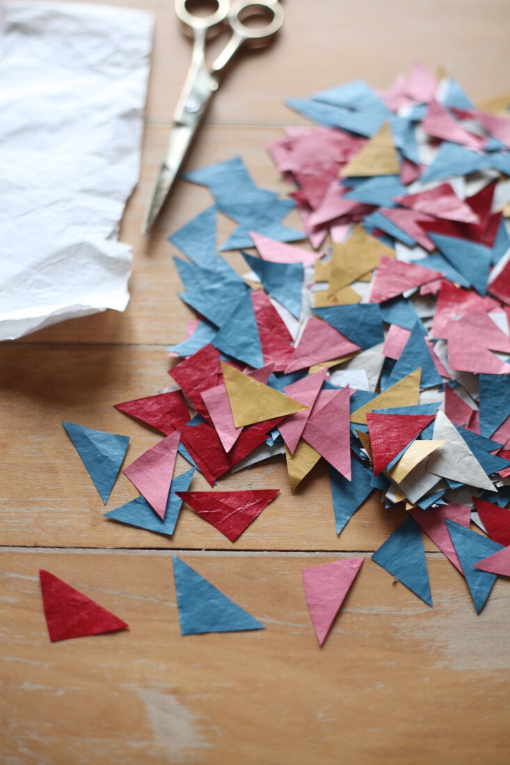 next, she cuts the paper into geometric shapes. she applies glue—akin to 20