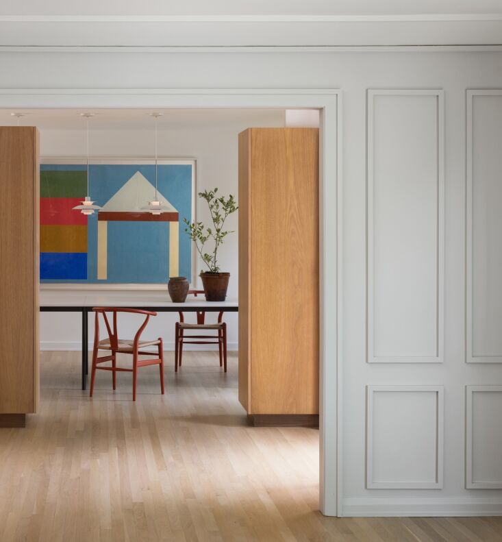 a david x. levine painting hangs in the dining room, where tomato red wishbone 26