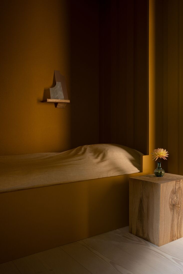 a custom alcove bed also in golden ochre. the wall lamp is designed by the arch 33