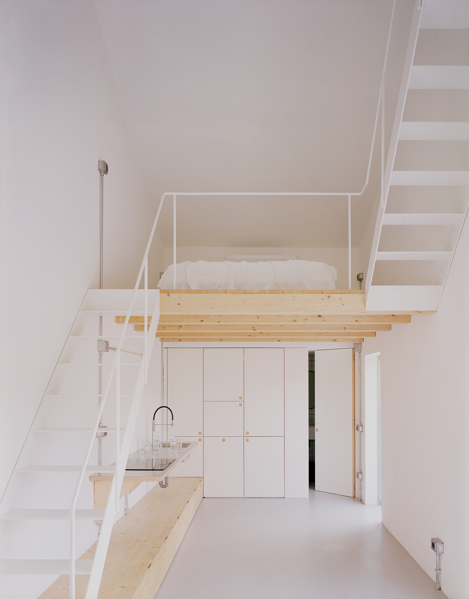 an open metal stair leads to a wooden sleeping loft. the stair continues to an  21