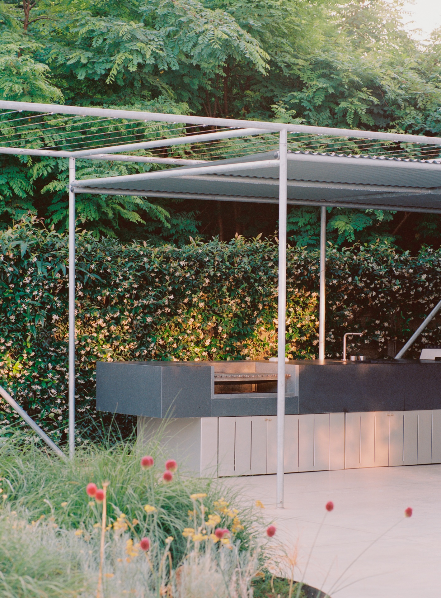 a pergola of steel piping shelters the outdoor kitchen finished in flamed and b 25