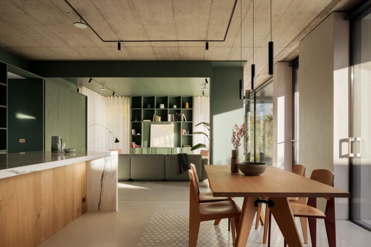 the living room opens to an airy kitchen and dining area. the floor is concrete 18