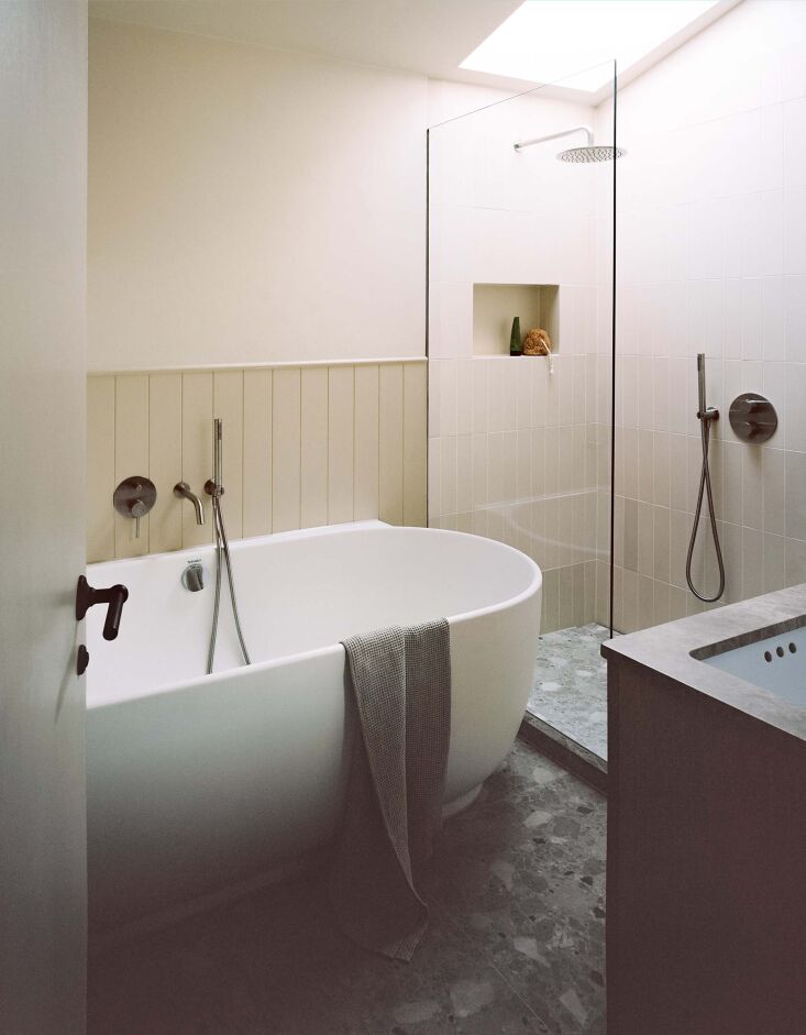a wider view of the bath shows the glass framed shower and terrazzo tile floors. 24