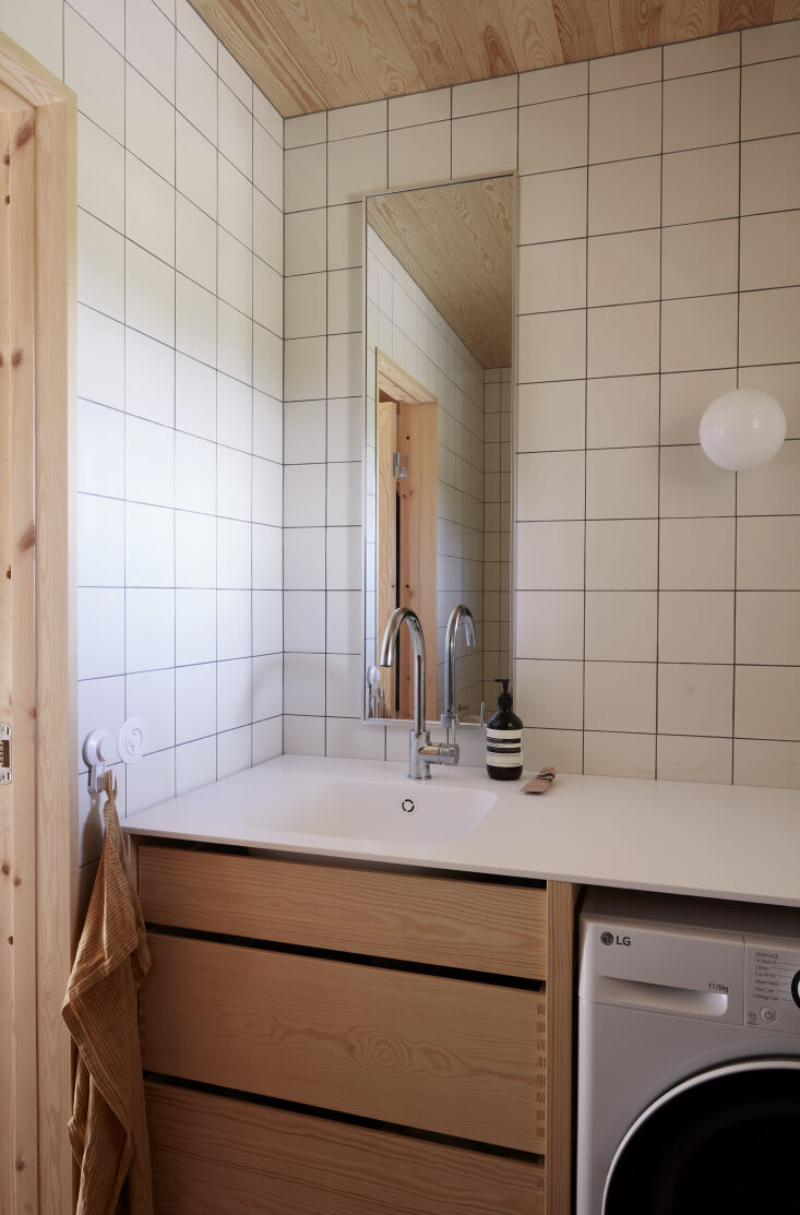 the bathroom is designed with square tile, a long rectangular vanity mirror, an 26