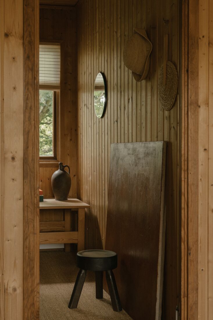 a summer hat and woven fan hang on the wall alongside a round vintage mirror. 26