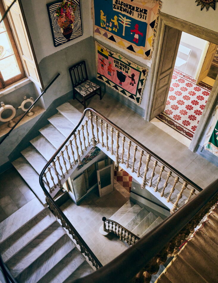 the marble stair winds past a hall hung with appliquéd asafo flags from ghana. 24