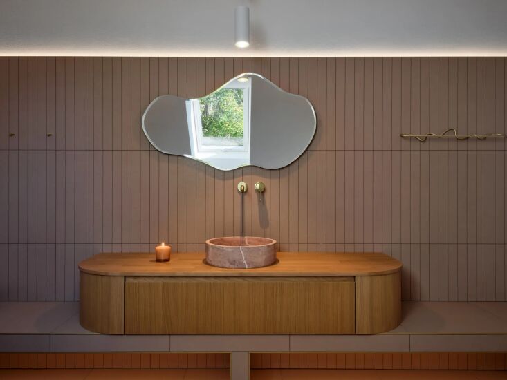 a custom vanity in oak veneer contrasts with pinkish brown vertically laid tile. 31