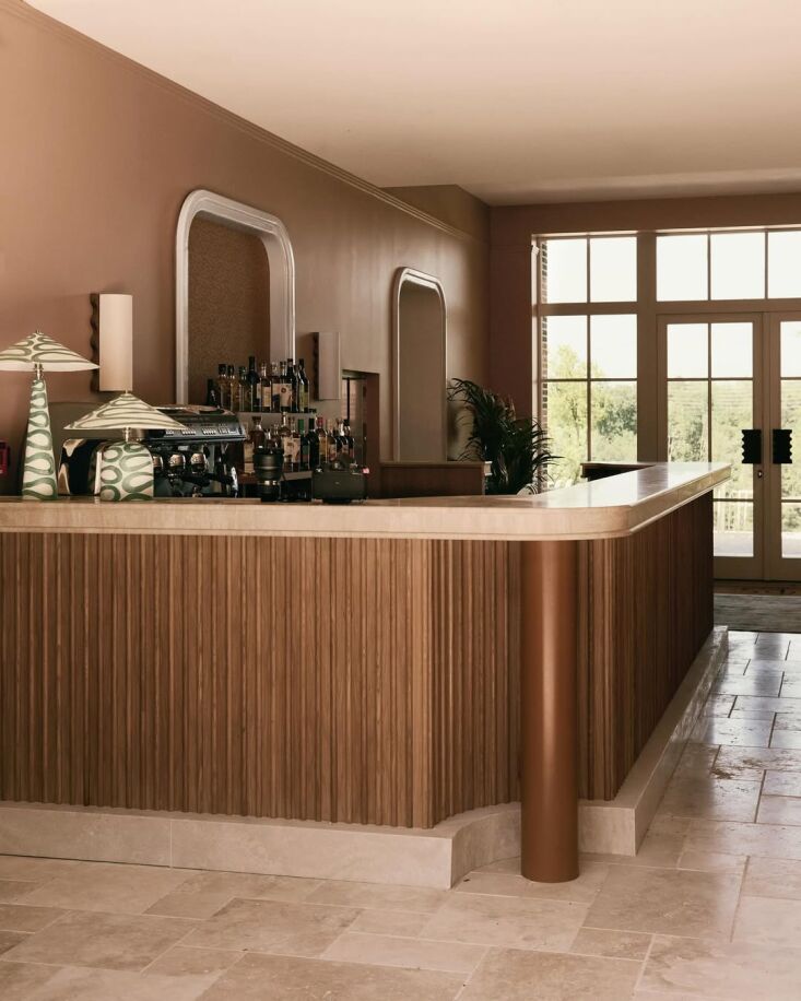 a 6 meter long travertine topped walnut bar with parasol table lamps from palef 20