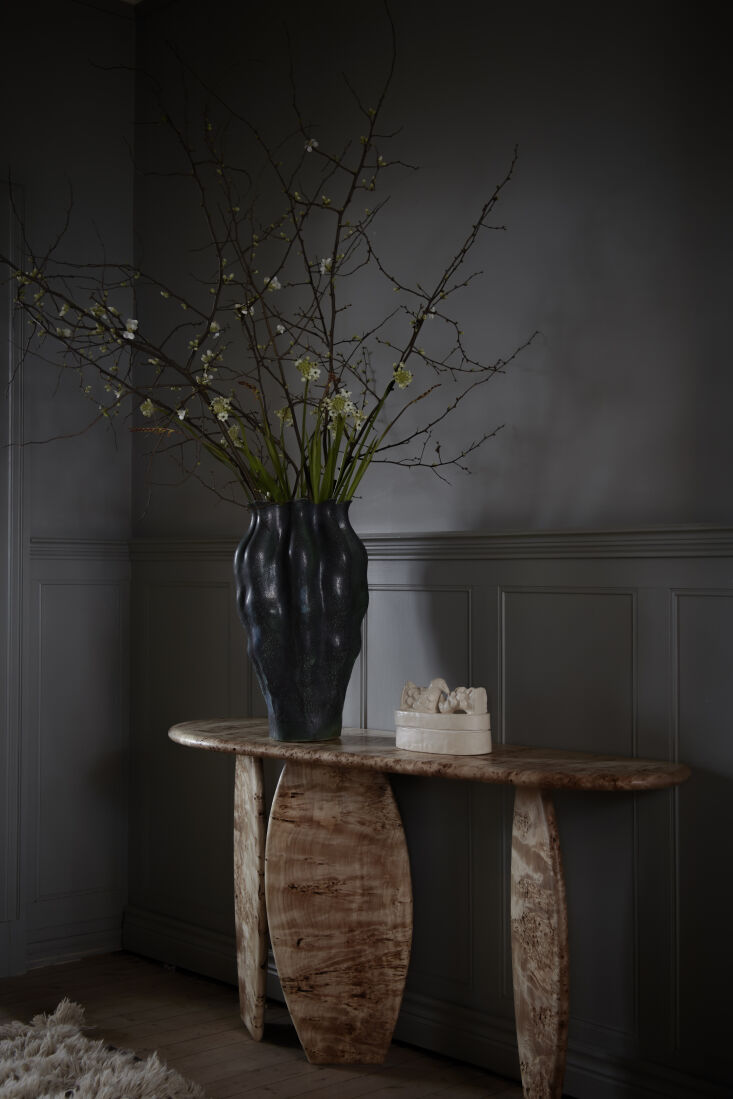 the table is the artilleriet voble console in burl wood. atop the console is th 18
