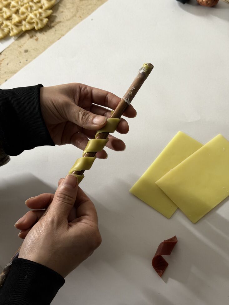 sheets of beeswax are cut and gently wrapped around a dowel rod to dry. 19