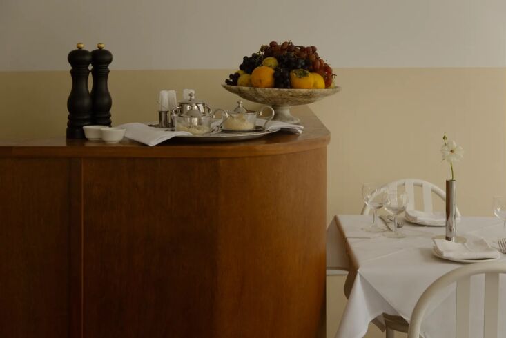 a custom curved wood bar features silver tea service and a vintage marble pedes 20