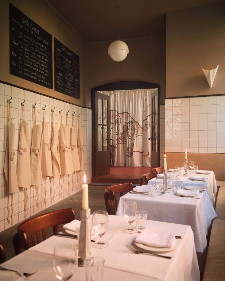 a row of aprons hangs on the wall between the main dining area and separate eve 23