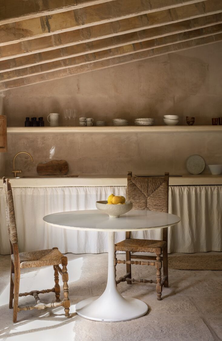 the kitchen has a counter and open shelf of limewashed microcement. the table 26