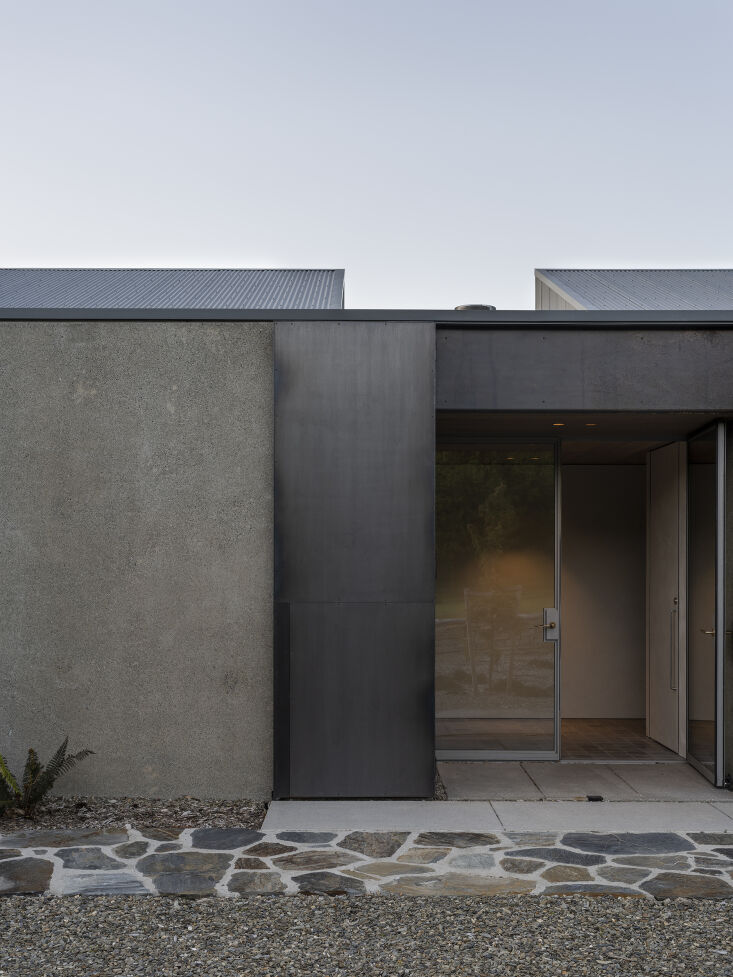 the main entry door is made of steel framed glass with a gate made of raw ste 18