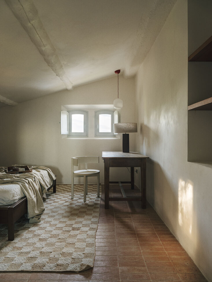 a bedroom designed with a check wool jute rug from ferm living, antique desk, a 25