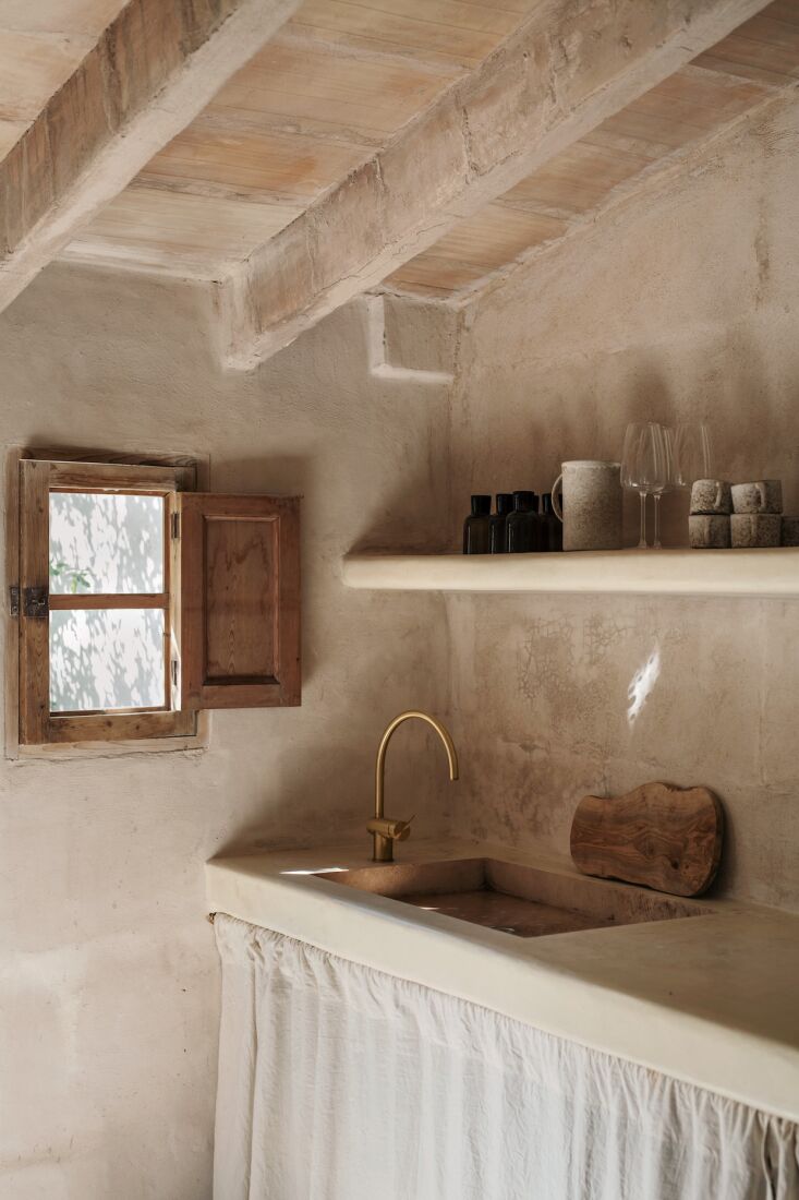 an old stone sink with an icónico mixer faucet is set into the counter. the wh 27