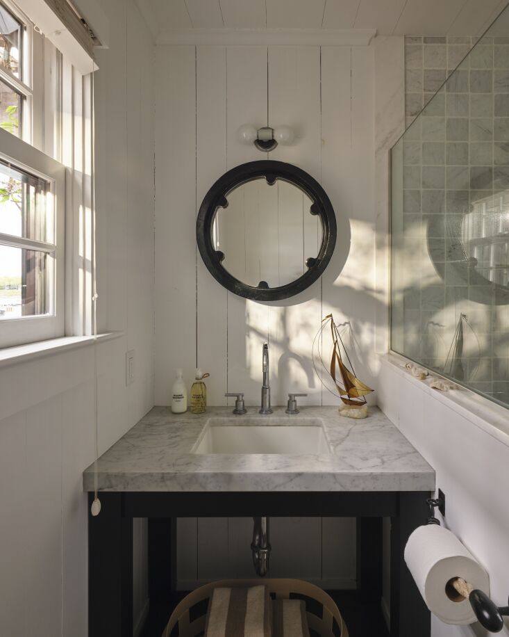 a porthole style mirror and nautical rope tp holder in the bath. 23