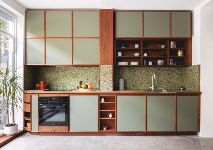 the compact kitchen pairs custom walnut cabinetry with pistachio green painted  20
