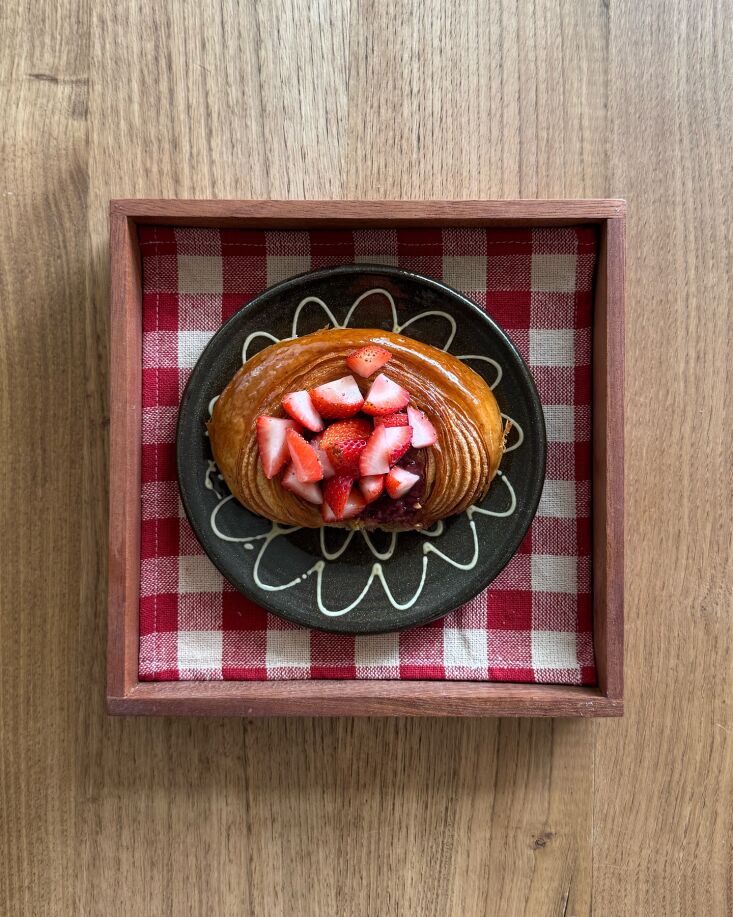 pastries are served in wooden trays with checked linen mats. this is a strawber 22